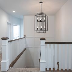 a light fixture hanging from the side of a stair case next to a banister