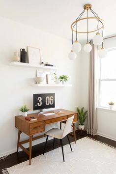 a desk with a clock on it and some plants in the corner next to it