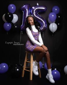 a woman sitting on top of a stool in front of purple and white balloon decorations