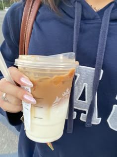 a woman is holding a starbucks drink in her hand