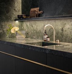 a bathroom with marble counter tops and gold faucet, along with a sink