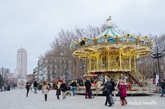 many people are walking around in front of a merry go round