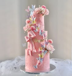 a three tiered pink cake decorated with flowers and butterflies