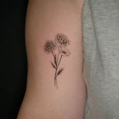 a woman's arm with three dandelions tattooed on the back of her left arm