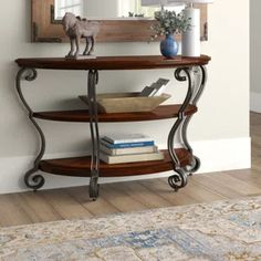 a wooden shelf with books on top of it in front of a mirror and rug