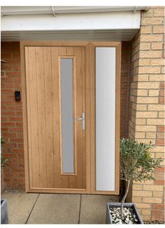 an image of a wooden front door with glass panels on the side and potted plants outside