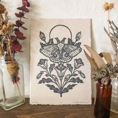 a vase filled with dried flowers next to a painting on top of a wooden table