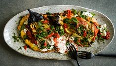 a white plate topped with an omelet covered in toppings and a fork