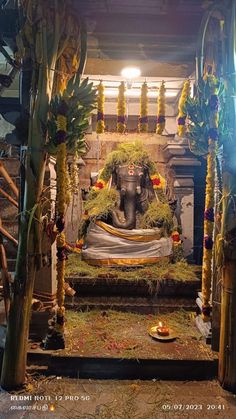 an elephant statue is surrounded by flowers and candles in a temple with lights coming from the ceiling