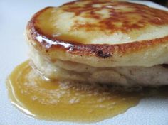 a stack of pancakes sitting on top of a white plate covered in butter and syrup