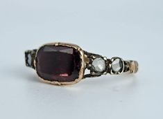 Beautiful antique natural garnet and rose cut diamond ring circa 1700s. This gorgeous and well-preserved ring features a large bezel set, flat cut garnet with four rose cut natural diamonds to the sides. All stones have solid gold backs and the garnet has a decorative closed back, typical of mid-18th century rings. The garnet measures 9.6x7mm and the diamonds are about 2.7mm each. Ring size 6 and sizable. Please allow two weeks for sizing. One month layaway payment plans on items $500 and over o Vintage Garnet Rings With Rose Cut Diamonds, Ornate Round Garnet Rings, Heirloom Yellow Gold Garnet Jewelry, Georgian Rings Antique, Luxury Antique Garnet Rings, Georgian Ring, Rosecut Diamond Ring, Rose Cut Diamond, Rose Cut