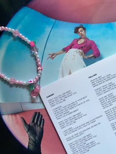 an open book with a hand on it next to a beaded bracelet and necklace