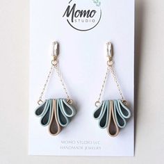 a pair of earrings with chain hanging from it's ear hooks on top of a card