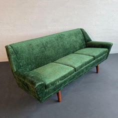 a green couch sitting on top of a gray floor