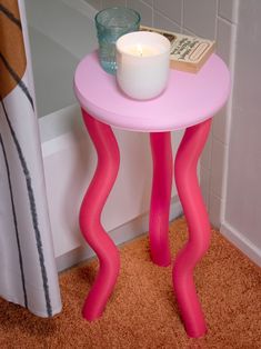 a small pink table with a candle on it