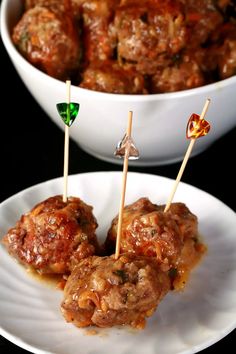 meatballs with toothpicks on a white plate next to a bowl of sauce