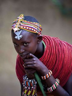 an african woman wearing colorful headdress and holding a green stick in her hand