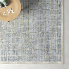 a blue rug on the floor next to a table with a vase and two pictures