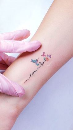 a woman's arm with the word love written on it and two small flowers