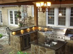 an outdoor kitchen with grill and sink in the middle of it's patio area