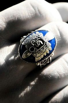 a close up of a person's hand wearing a ring with a dragon on it