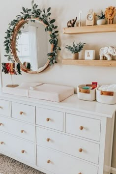 a baby's room with a dresser, mirror and stuffed animals on the wall