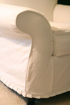 an upholstered white couch sitting on top of a carpeted floor