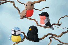 three knitted birds sitting on the branches of a tree, one black and one red