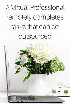 a vase filled with white flowers next to a laptop