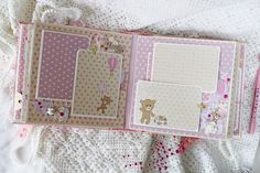 an open scrapbook with teddy bears and polka dots on the pages is laying on a bed