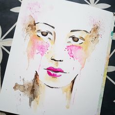 a watercolor painting of a woman's face with pink and yellow paint splatters on it