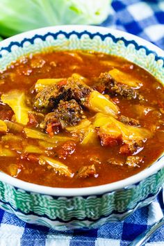 a bowl of soup with meat and cheese in it on a checkered table cloth