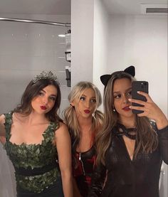 three beautiful women standing next to each other taking a selfie in front of a mirror