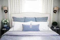 a bed with blue and white gingham sheets, pillows and lamps on either side