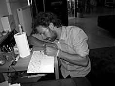 a man sitting at a table writing on a piece of paper