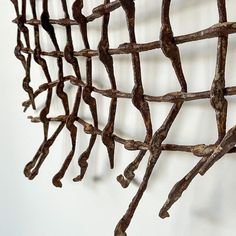 a metal sculpture is hanging on the wall next to a white wall and there are several branches attached to it