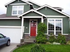 a car parked in front of a house with a red door and green sidings