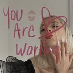 a woman holding her hands up to her face with the words you are worthy written on it