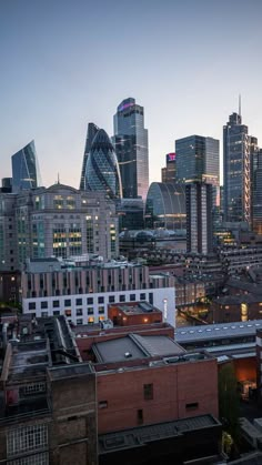 the city skyline is lit up at night, with skyscrapers in the foreground