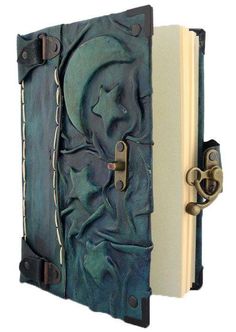 an open book with metal handles on the front and back cover is decorated with blue leather