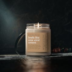 a candle sitting on top of a wooden table next to a black mug with the words smells like some virtual content