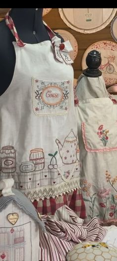 several different types of embroidered clothing on display in a shop window, including aprons and dresses