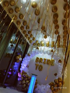 balloons and streamers hang from the ceiling in front of a bride to be sign