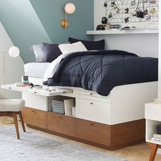 a bed with drawers underneath it in a bedroom next to a desk and chair on the floor