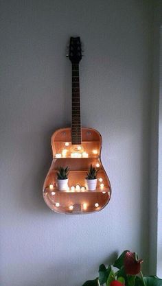 a guitar hanging from the wall with lights on it's back and bottom shelf