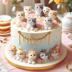 a cake decorated with kittens and flowers on top of a table next to cookies