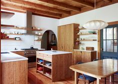 a kitchen with wooden floors and open shelves on the wall, along with an island