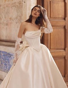 a woman in a white wedding dress with long sleeves and flowers on her head is posing for the camera