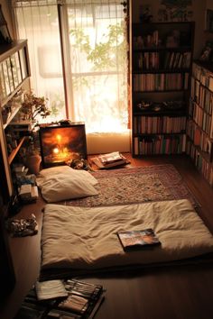 there are two beds in this room with books on the floor and an open window