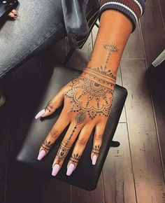 a woman's hand with henna tattoos on her left arm and wrist,